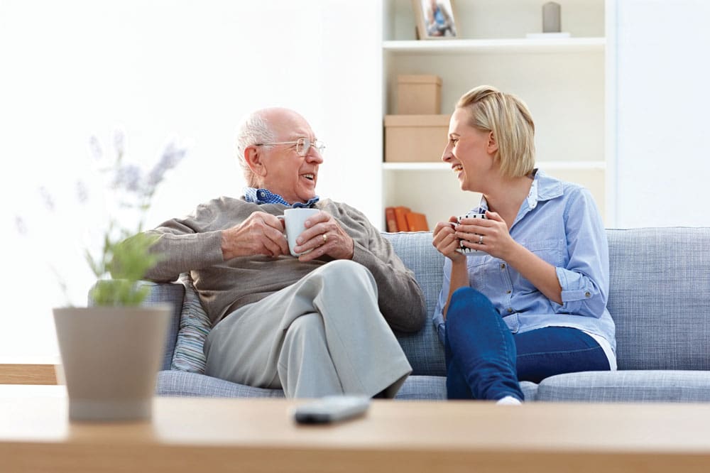 senior man and daughter laughing over coffee