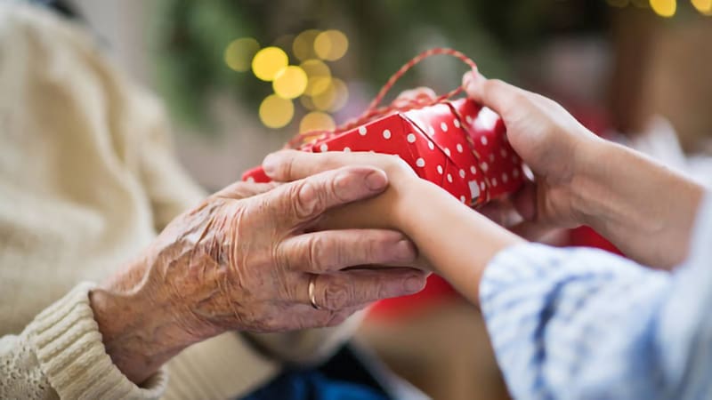 hands of senior and young woman holding a present at Christmas time