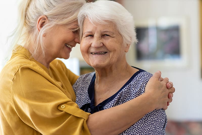 senior woman being embraced by her daughter